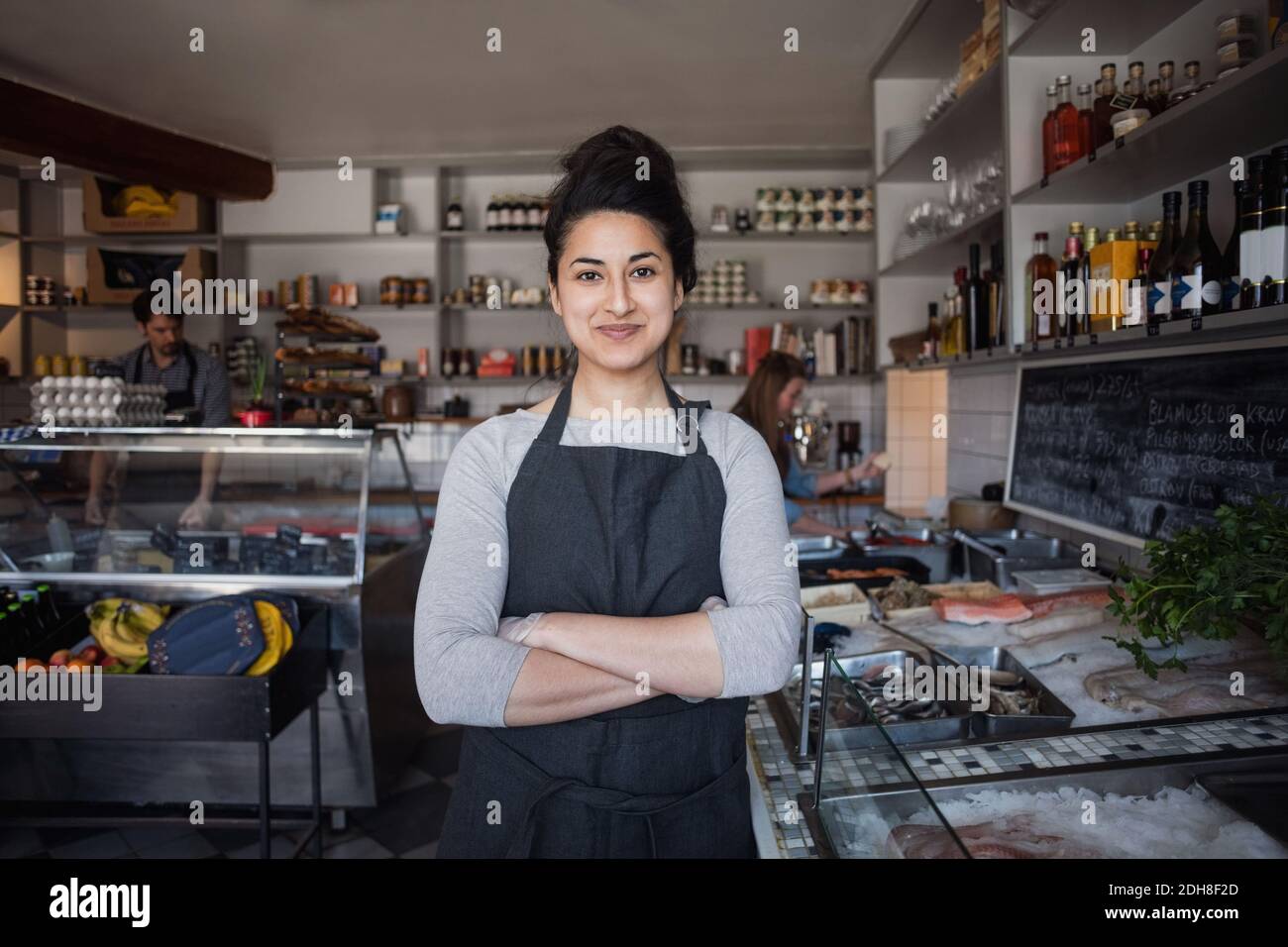 Portrait of smiling owner standing against colleagues at fish store Stock Photo