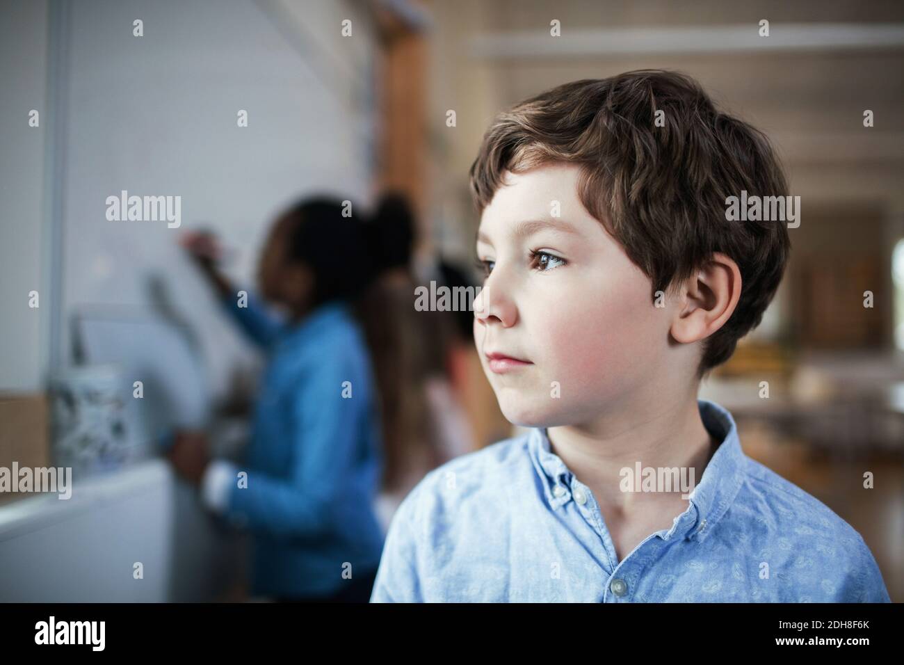 Close-up of male student looking away while standing in classroom Stock Photo