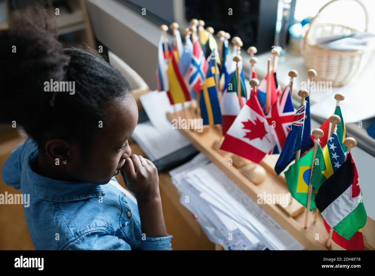 High angle view of thoughtful girl looking at various flags in classroom Stock Photo