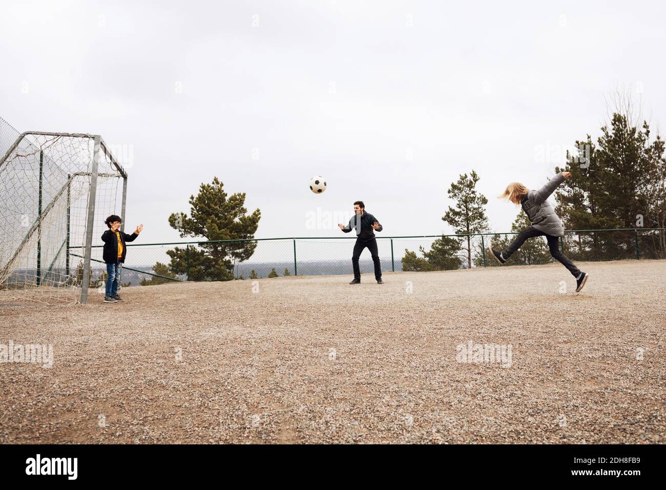 Teacher encouraging students while playing soccer on school playground Stock Photo