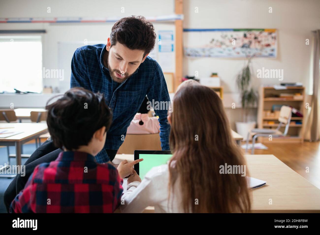 Teacher discussing with students using digital tablet in classroom Stock Photo