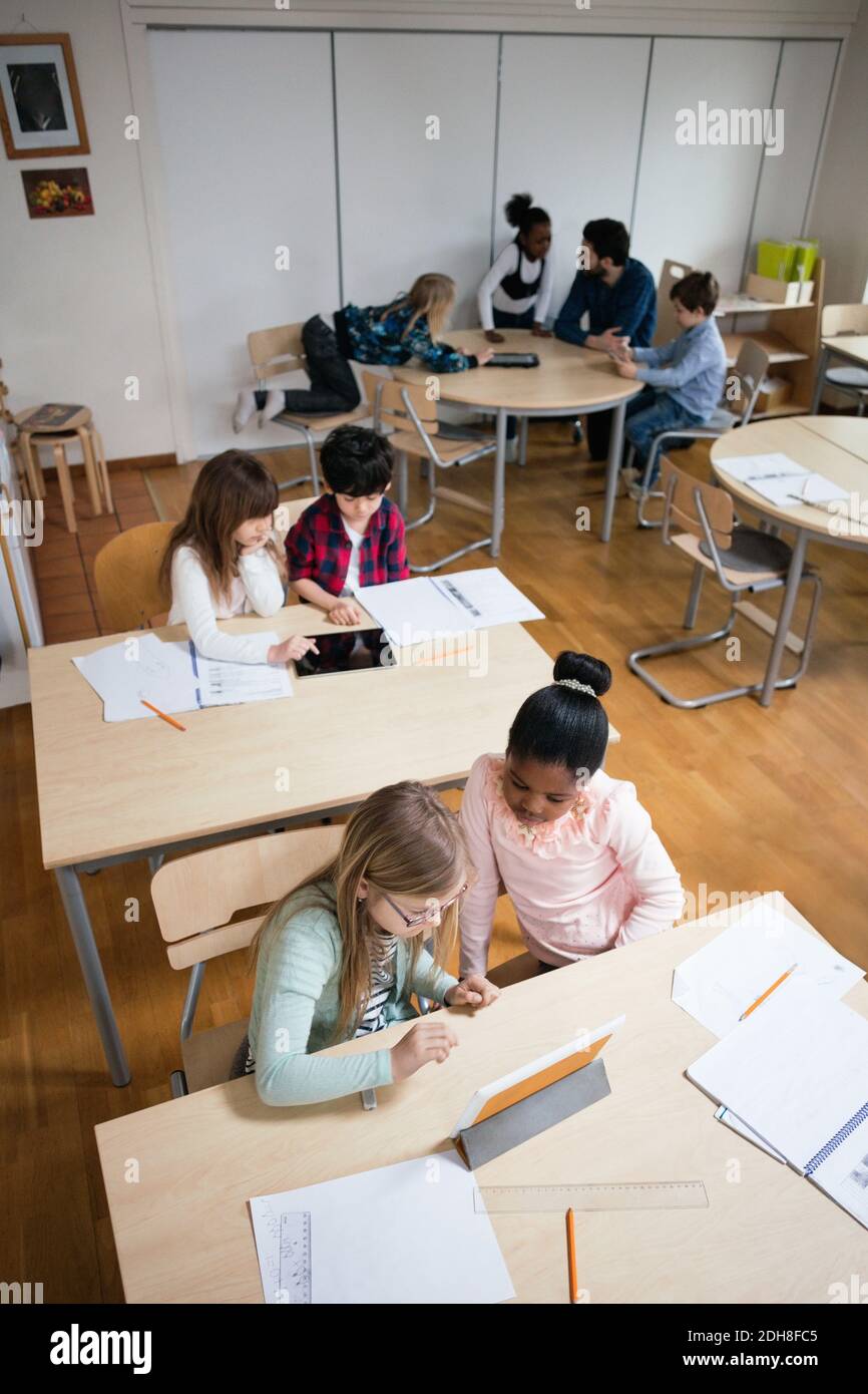 High angle view of students using digital tablet while sitting in classroom Stock Photo