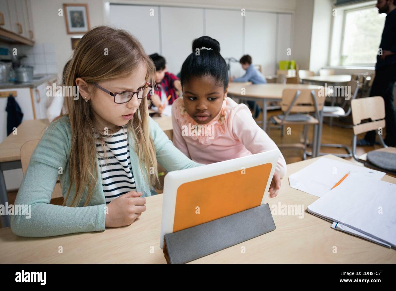 Serious students looking at digital tablet while sitting in classroom Stock Photo