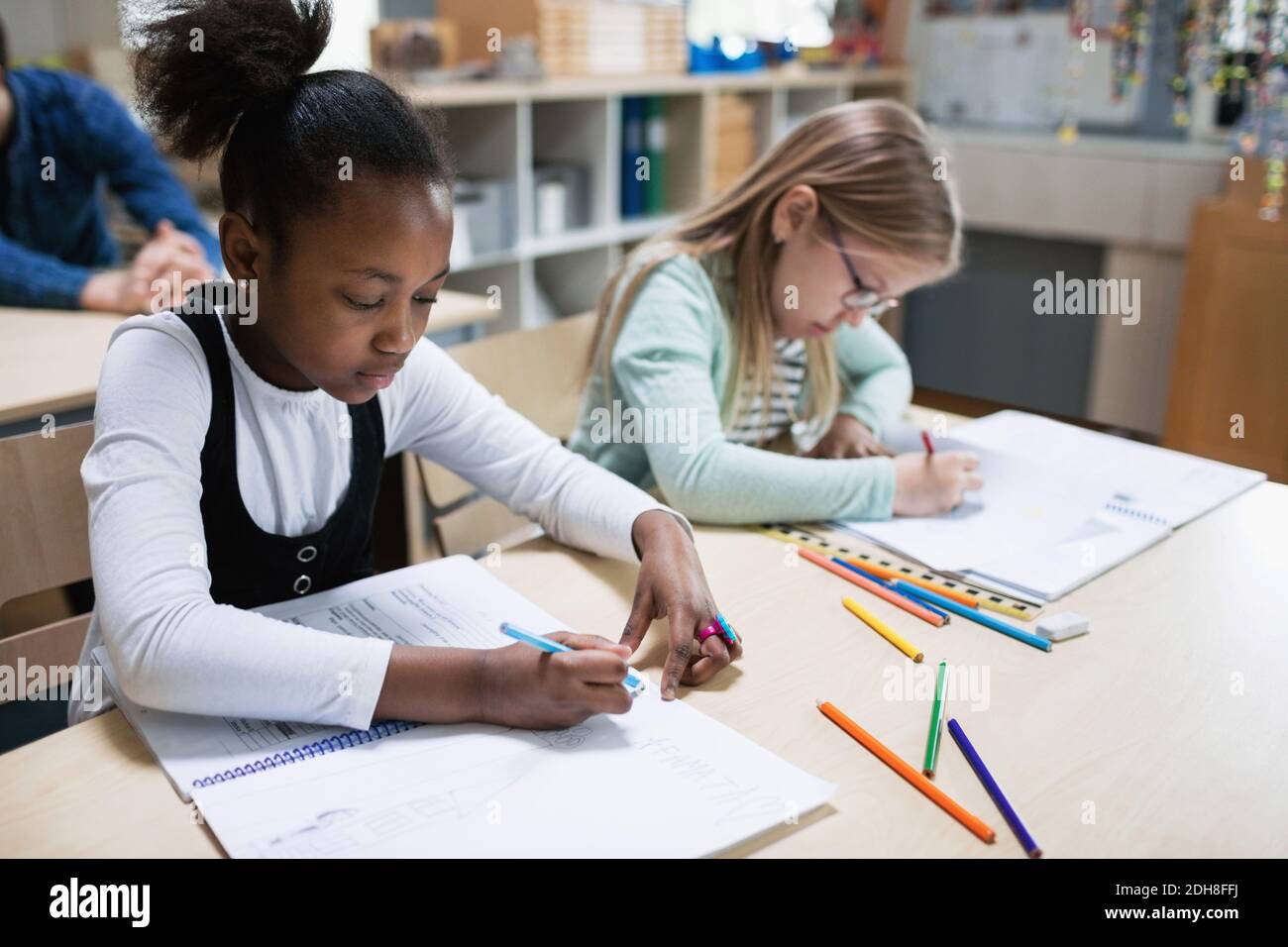 Schoolgirls studying at desk in classroom Stock Photo - Alamy