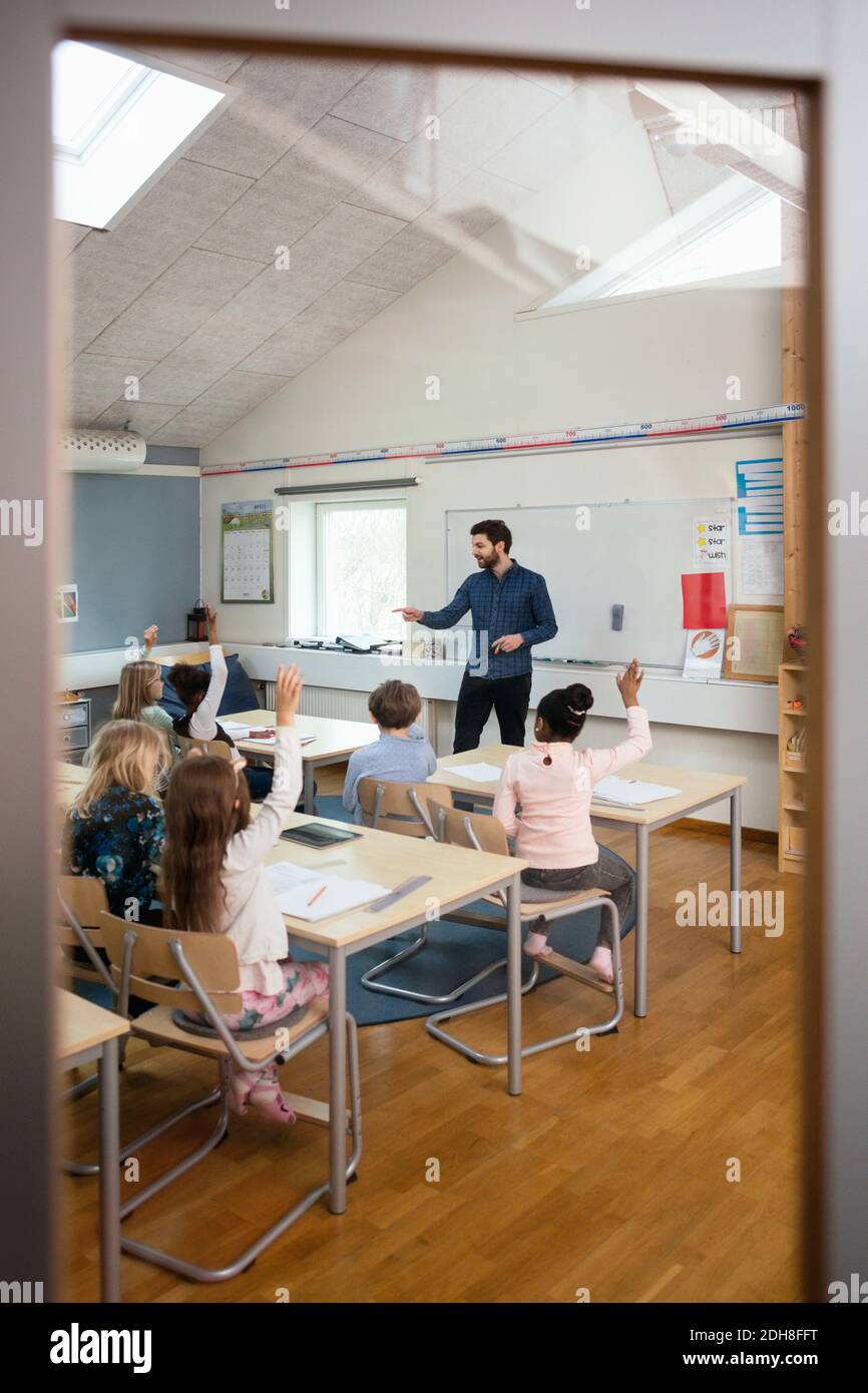 Teacher asking to students seen from entrance of classroom Stock Photo