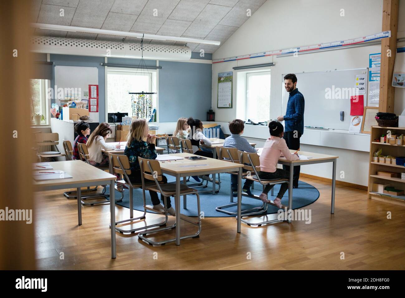 Confident teacher teaching students in classroom at school Stock Photo ...