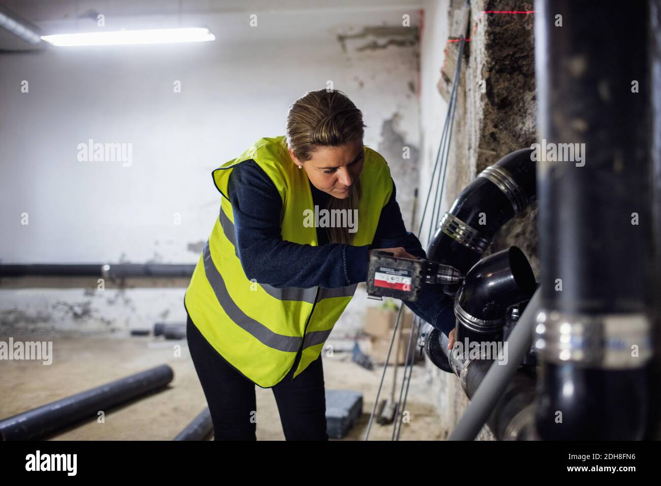 Concentrated female plumber sawing pipe at basement Stock Photo