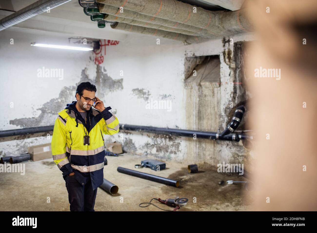 Smiling manual worker talking on phone in basement Stock Photo