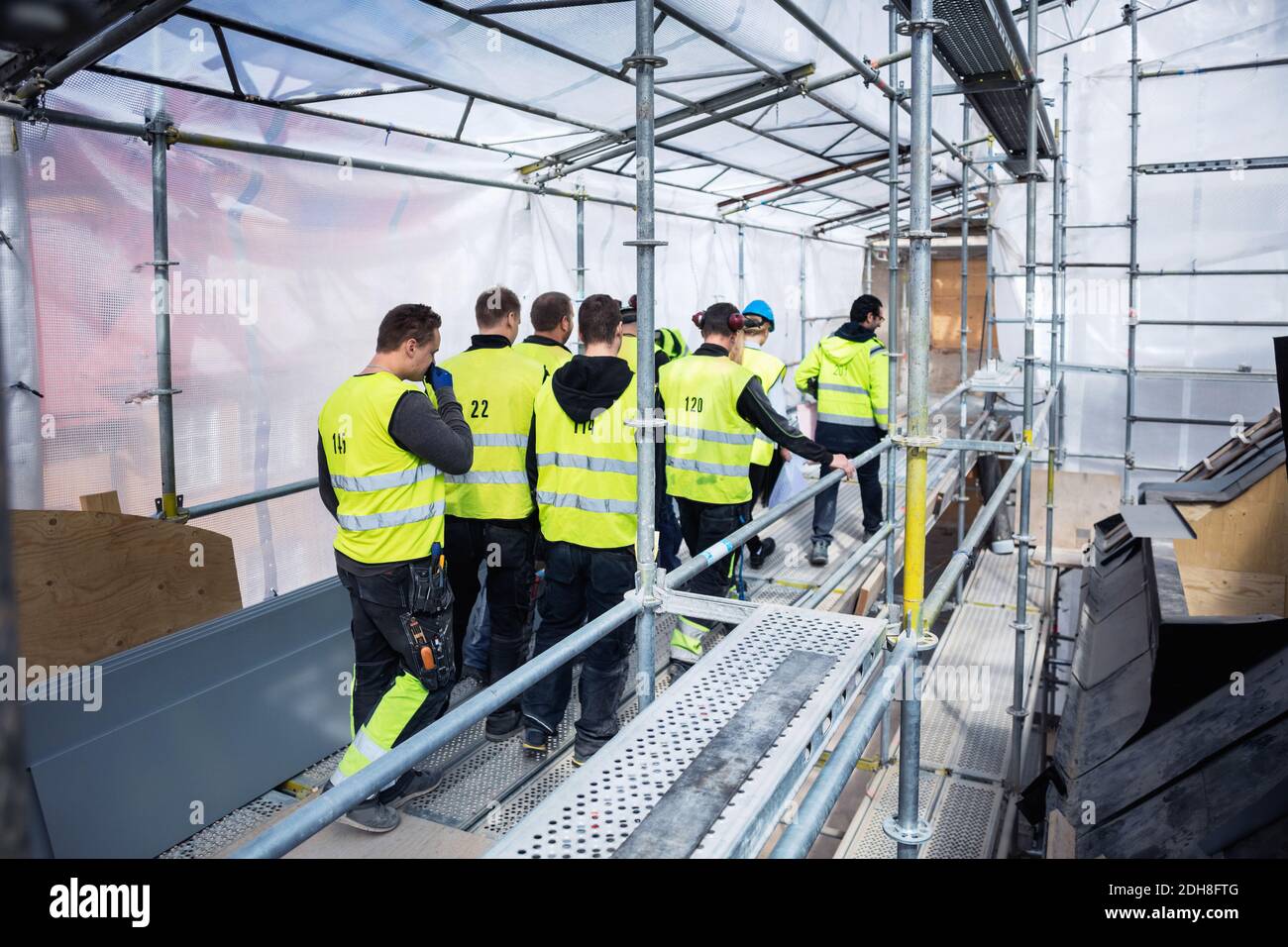 Rear view of manual workers walking at construction site Stock Photo