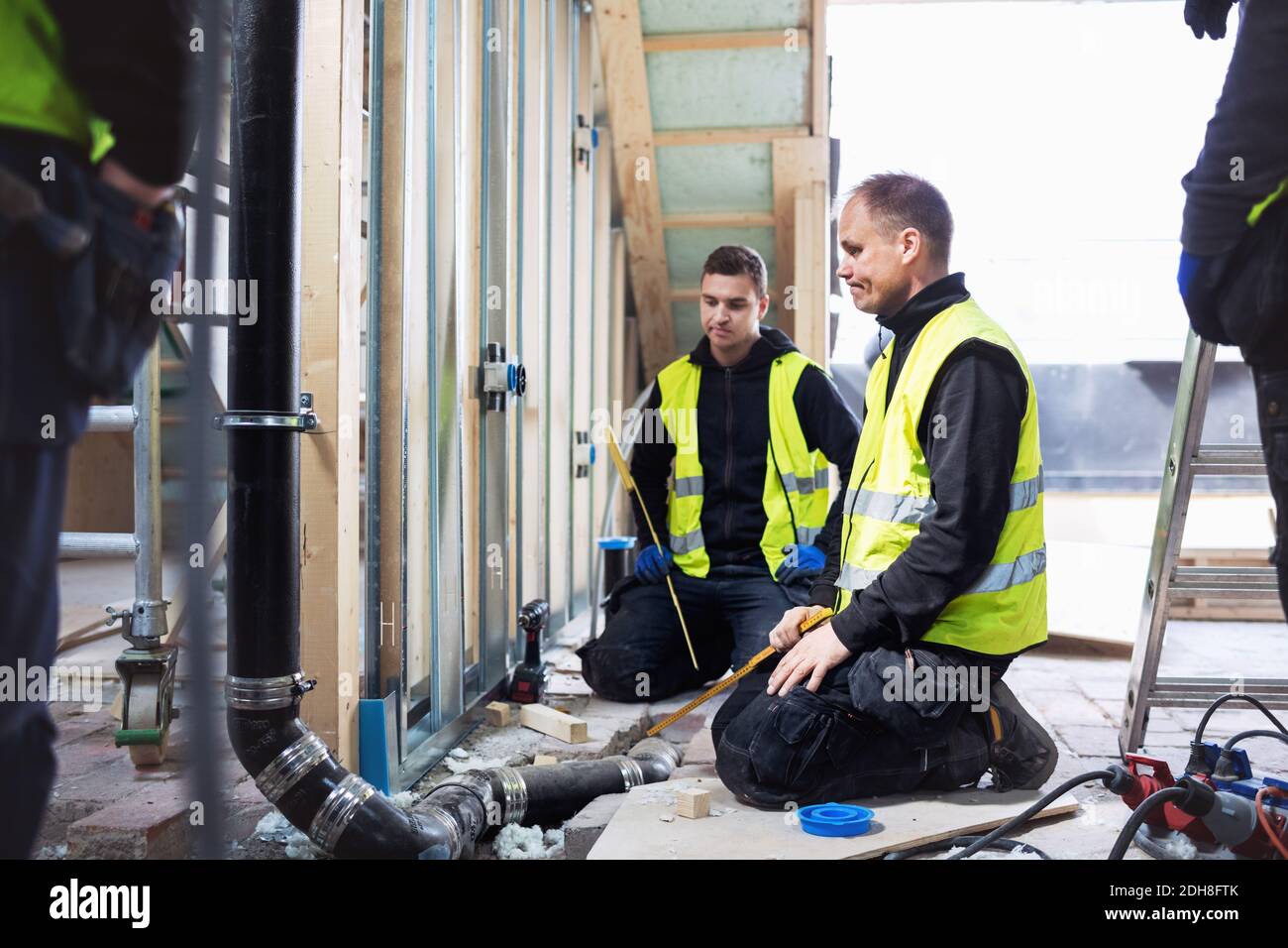 Thoughtful manual workers looking at pipe while working in construction site Stock Photo