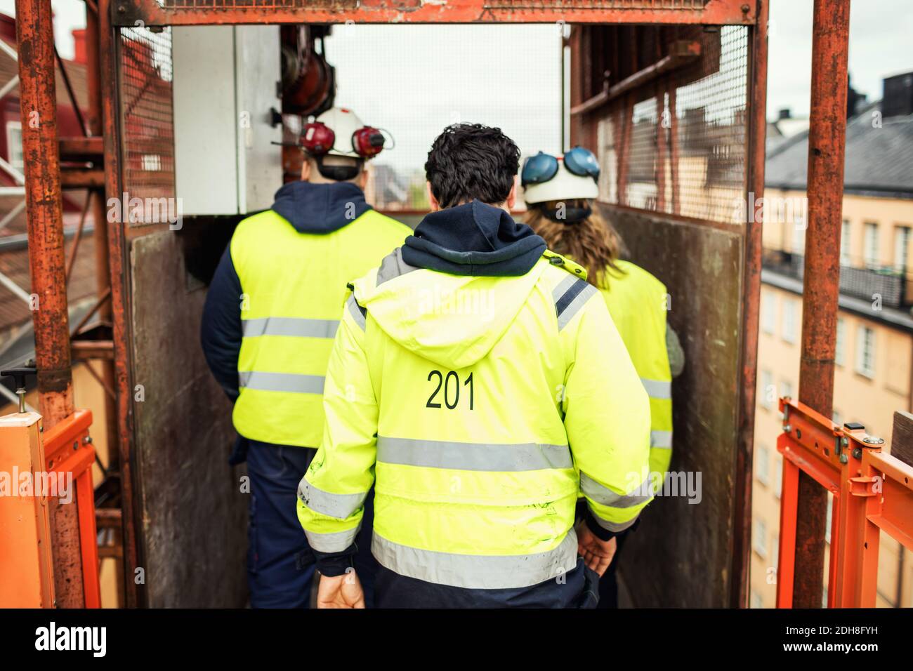 Rear view of construction workers standing in elevator at site Stock Photo