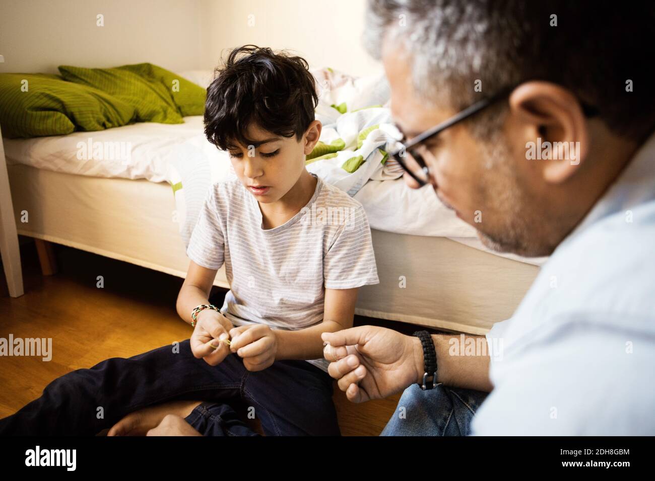 Father and son playing with rubber bands at home Stock Photo