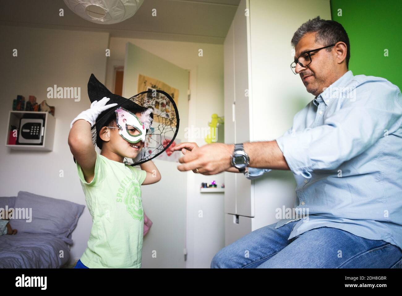 Father assisting son in wearing costume at home Stock Photo