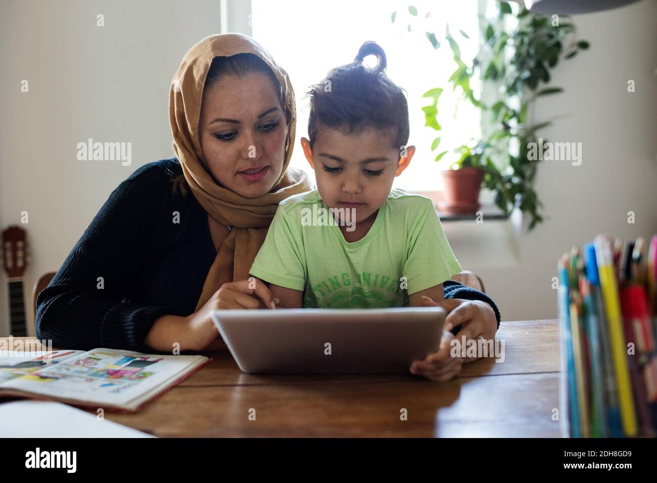 Mother assisting son in using digital tablet while studying at home Stock Photo