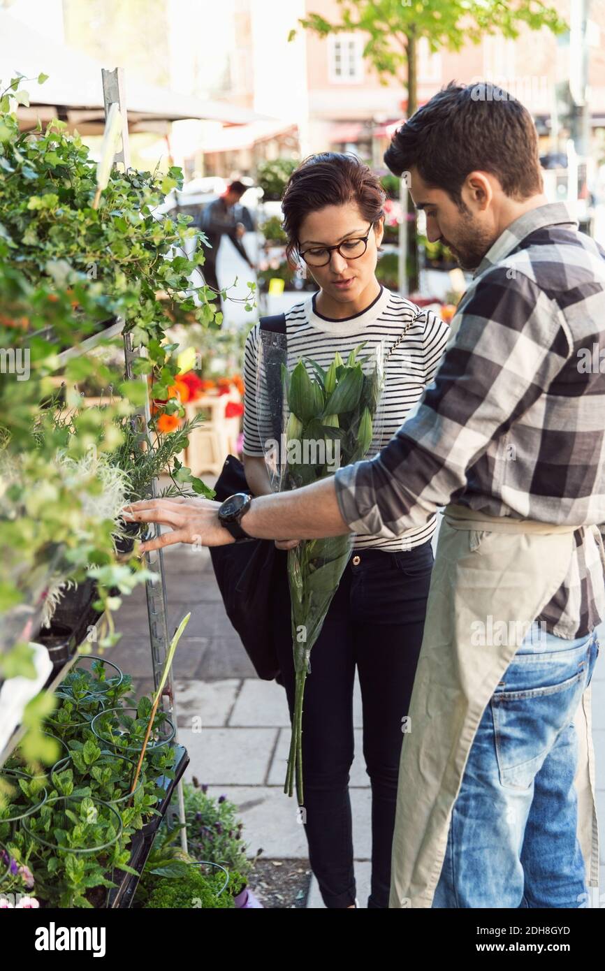 Woman buying flowers from male owner on sidewalk Stock Photo Alamy