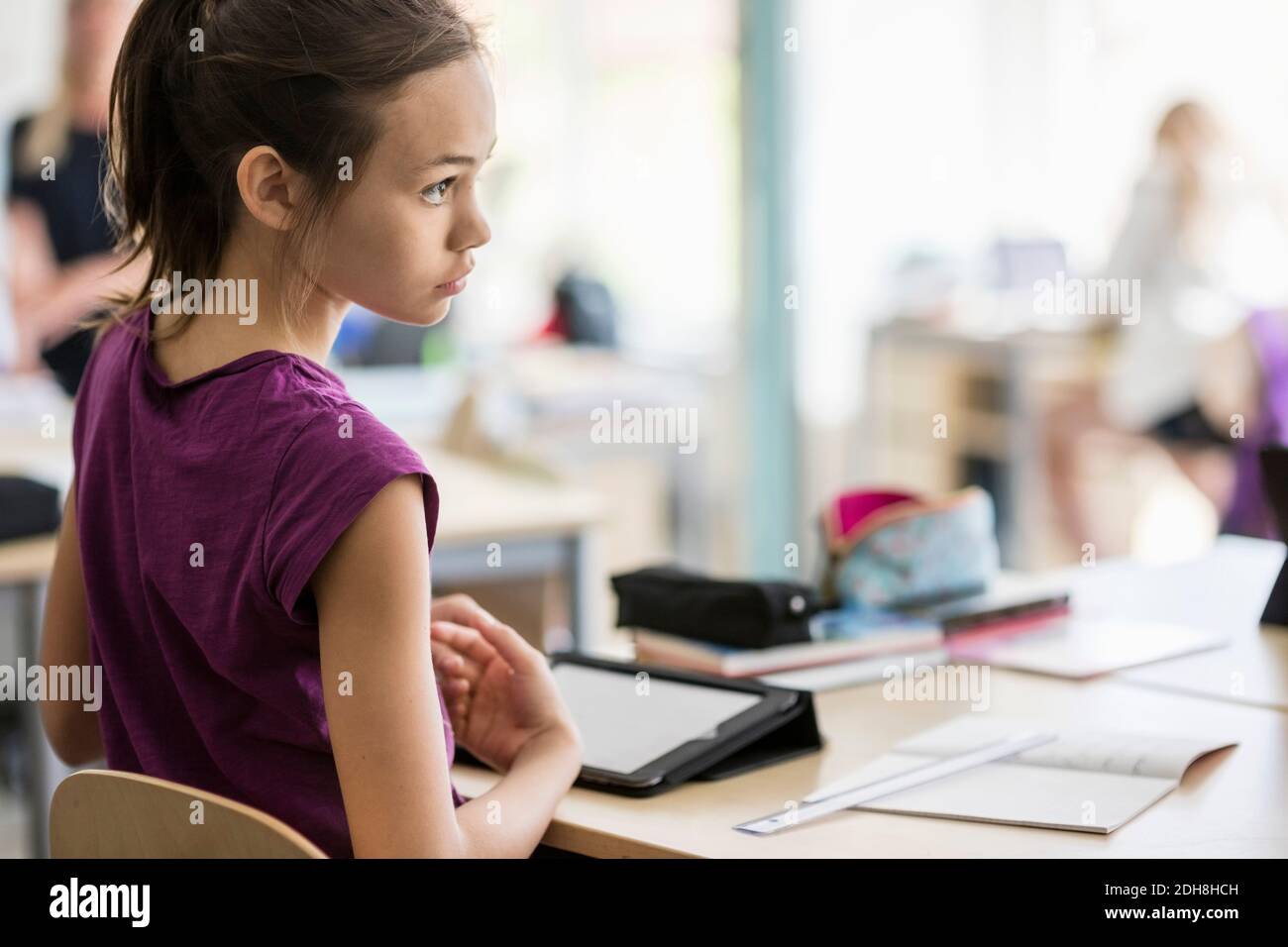Rear view of girl sitting on chair by desk in classroom Stock Photo - Alamy