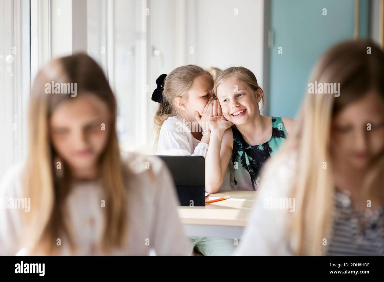 Happy girls whispering in classroom Stock Photo - Alamy