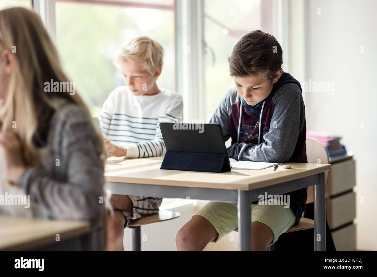 School children e-learning from digital tablet in classroom Stock Photo