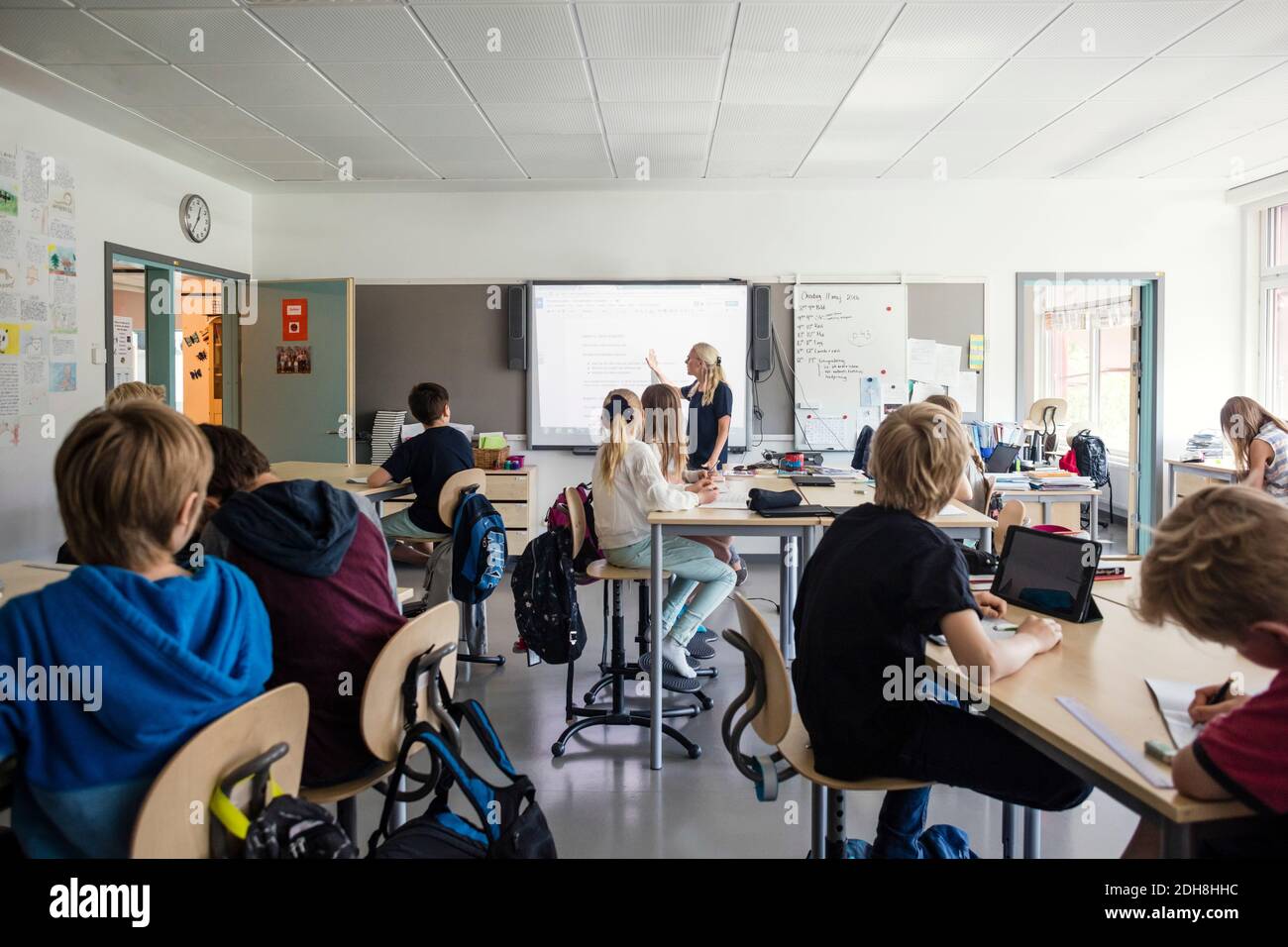 Teacher explaining students through whiteboard in classroom Stock Photo