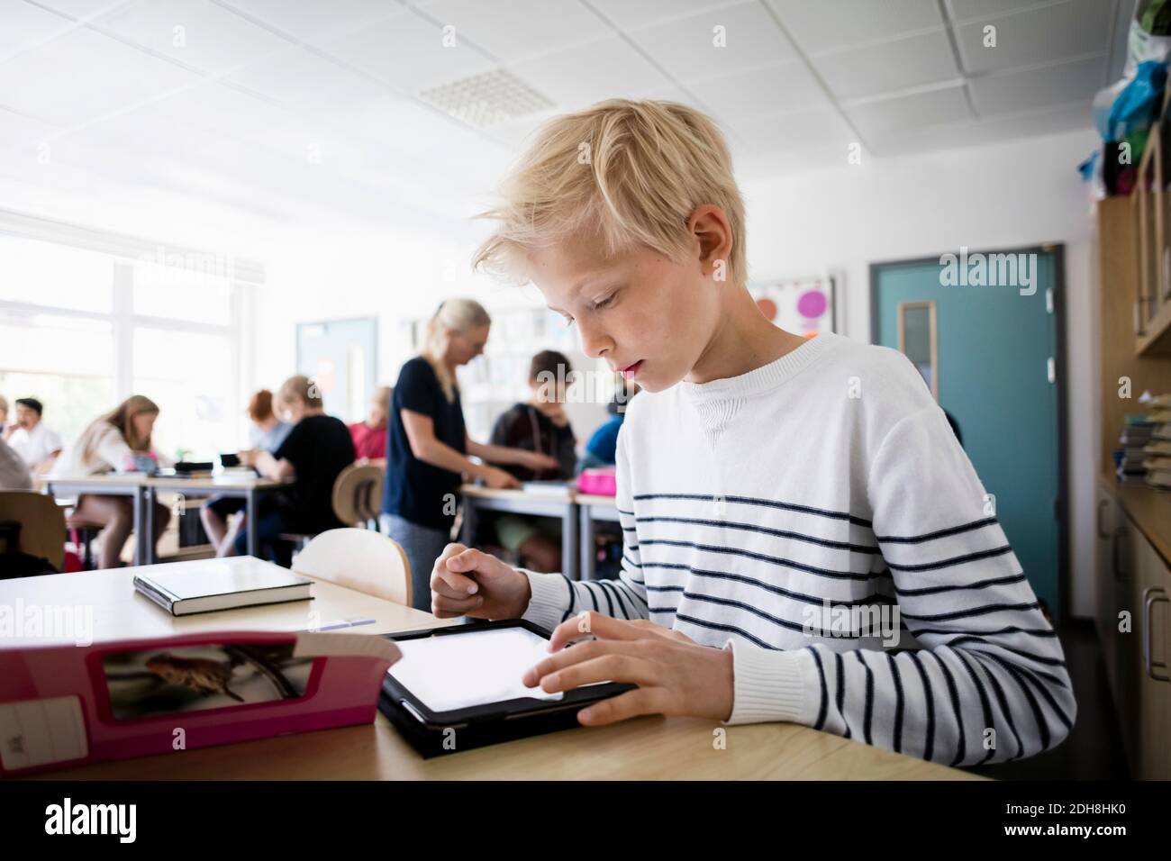 Boy using tablet pc at desk in classroom Stock Photo