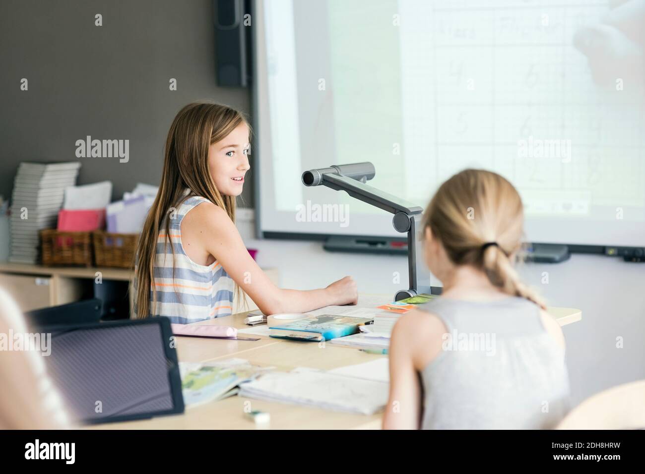 School girls sitting by desk in classroom Stock Photo - Alamy