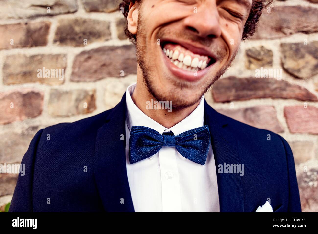 Cheerful gay man against brick wall Stock Photo