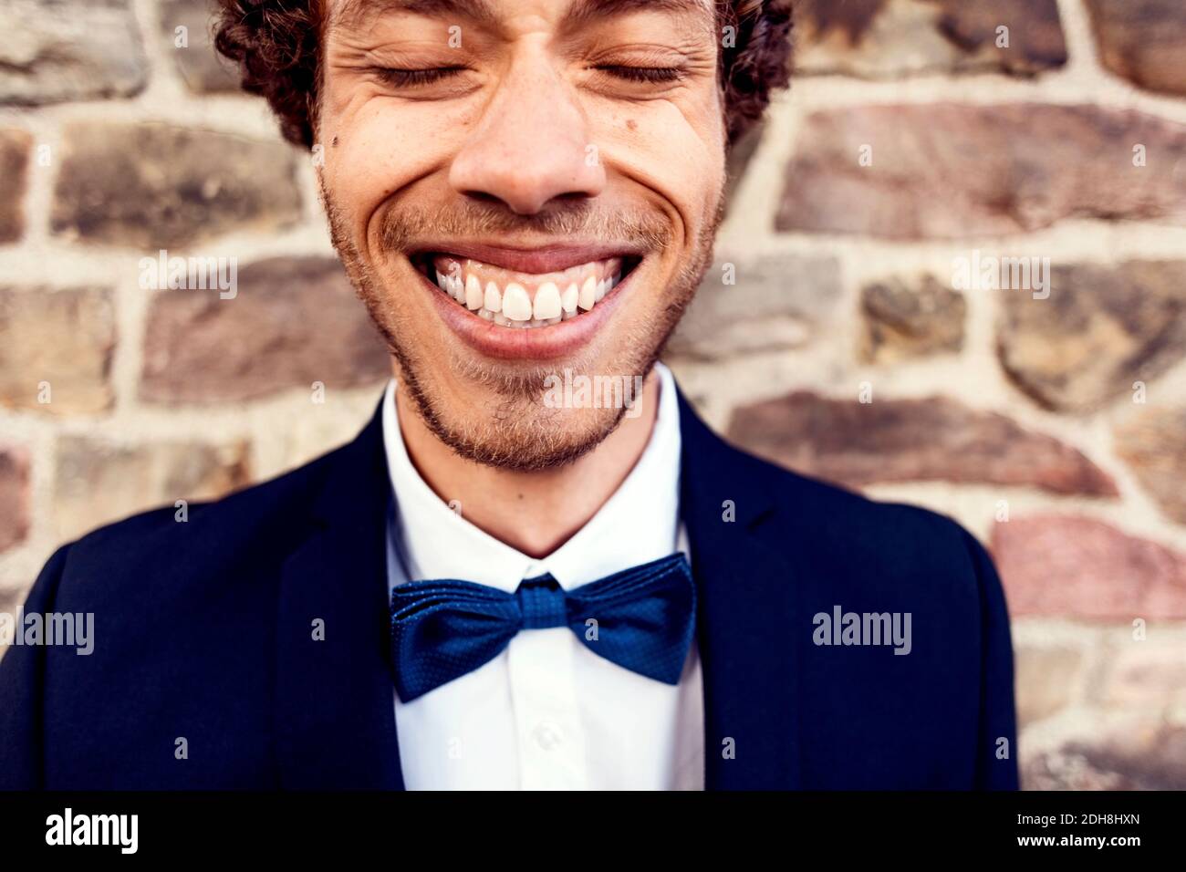 Happy gay man against brick wall Stock Photo