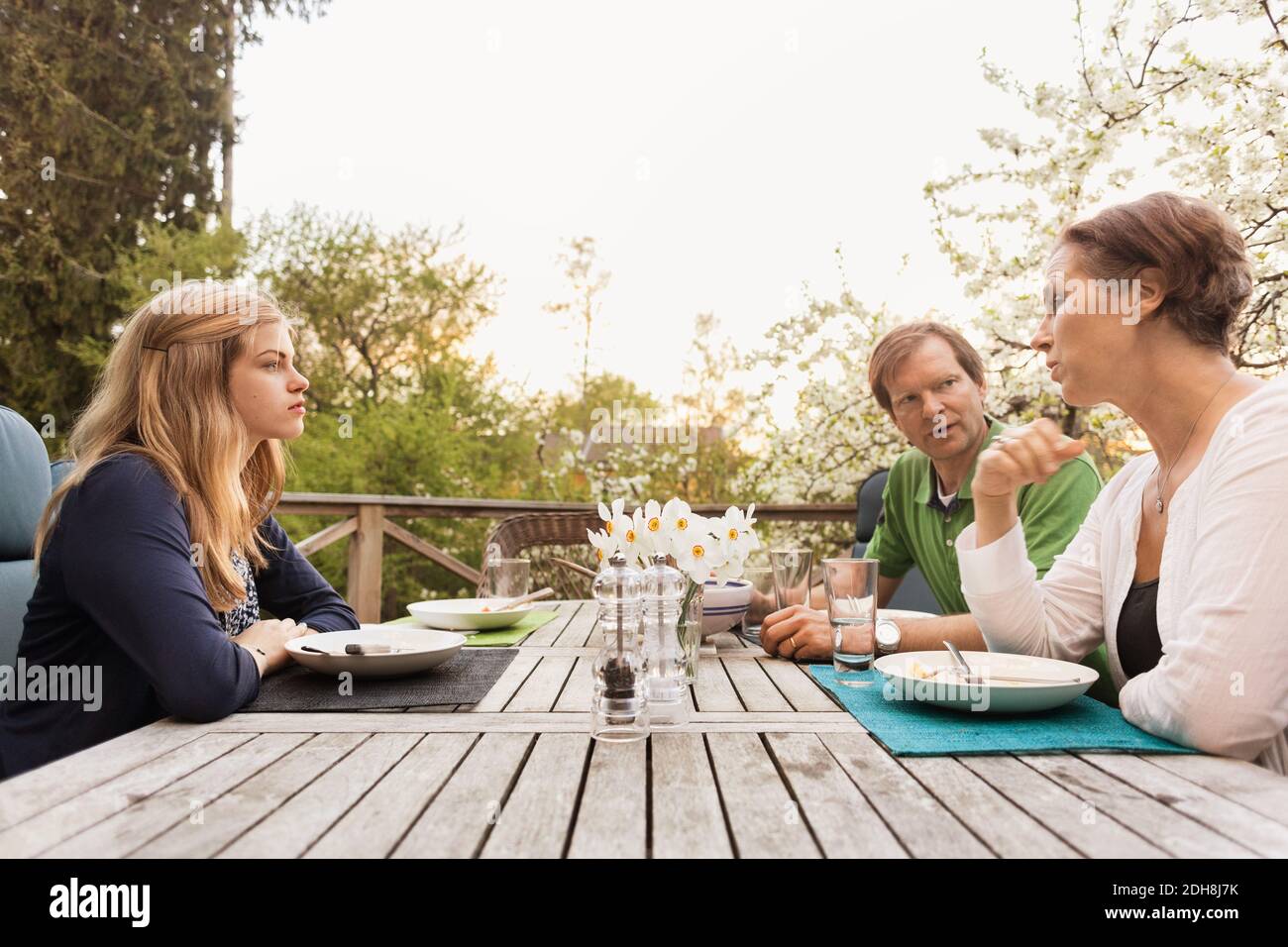 Family of three sitting at table in yard against clear sky Stock Photo