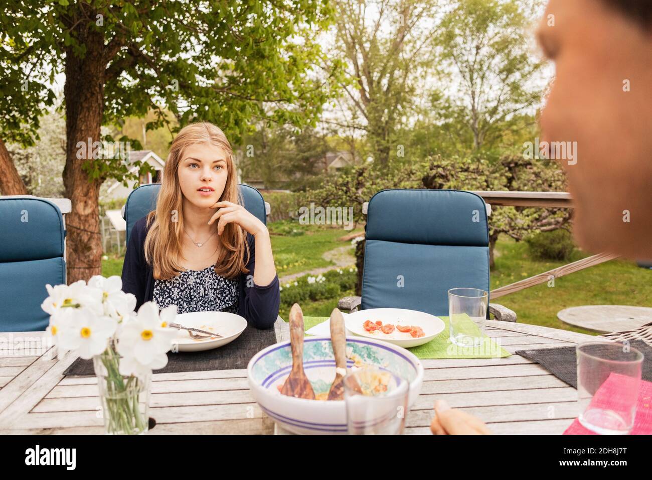 Teenage girl talking to father at table in yard Stock Photo