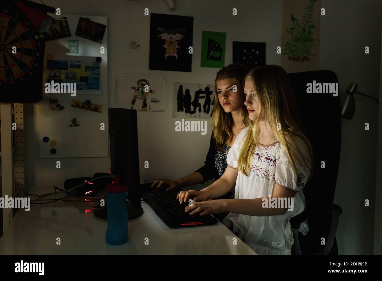 Teenage girls using computer in darkroom at home Stock Photo