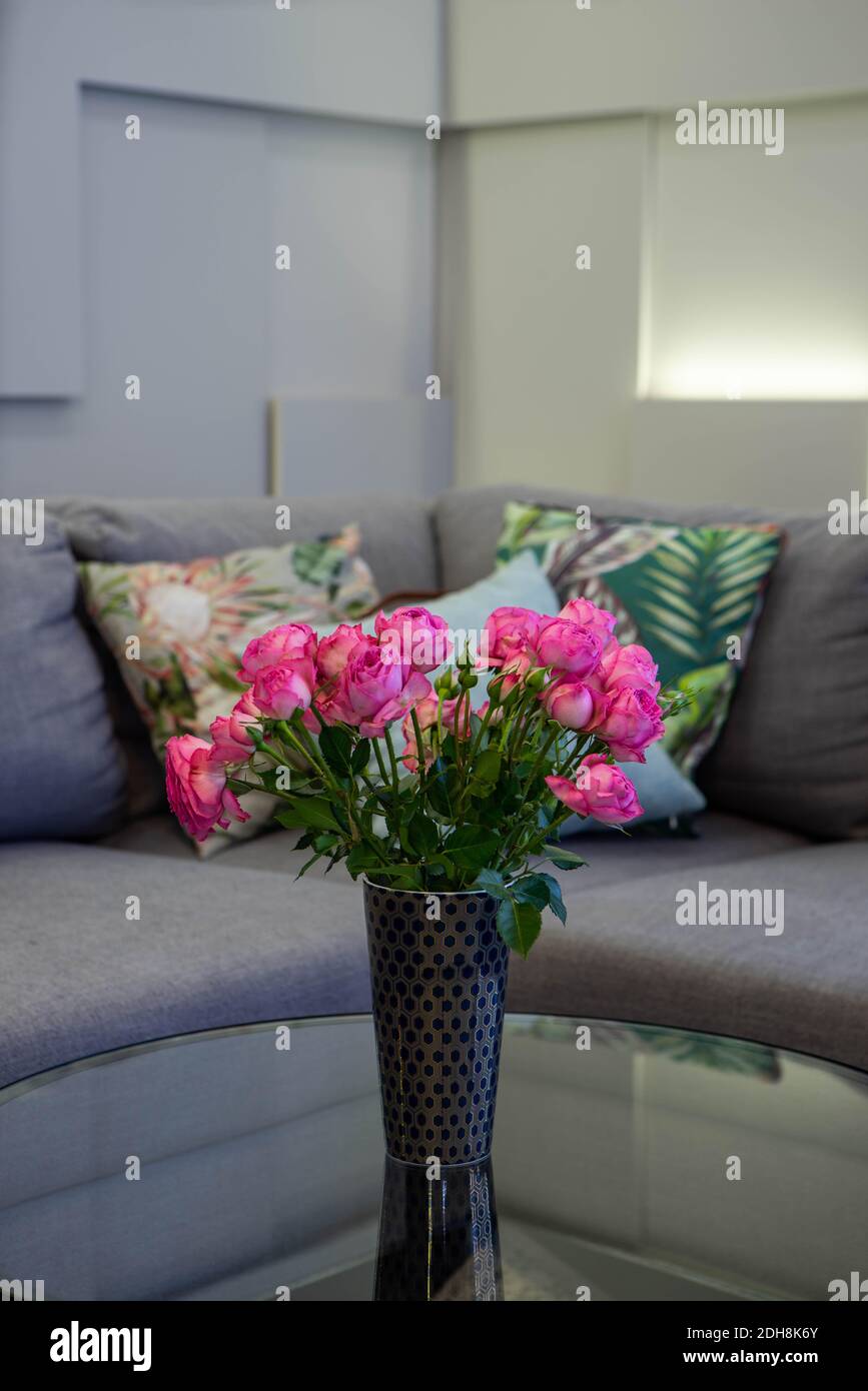 Beautiful bouquet of pink roses in black vase. Cozy couch with cushions ...