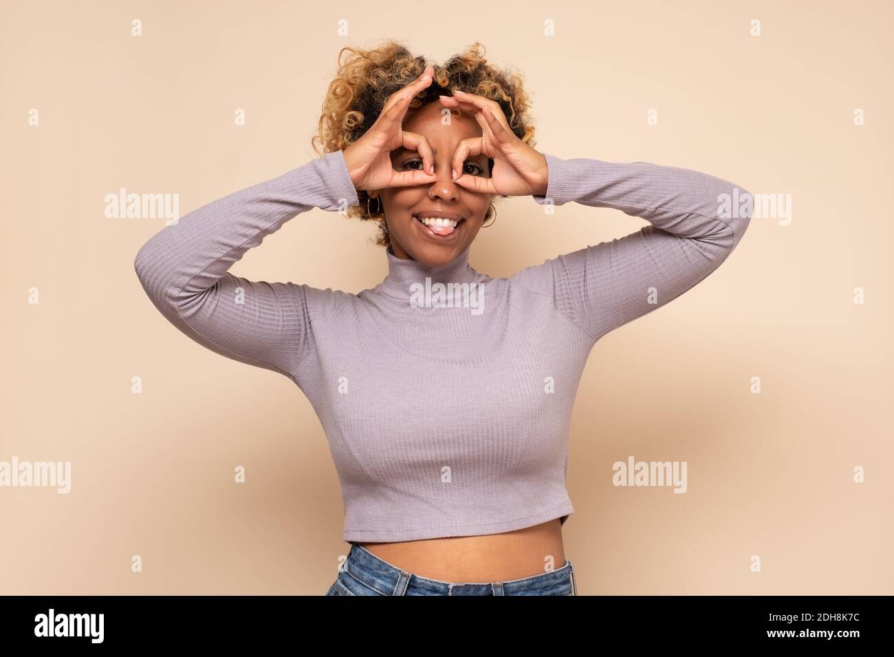 What is there. African woman making glasses shape, looking through binoculars gesture with shocked expression. Studio shot Stock Photo