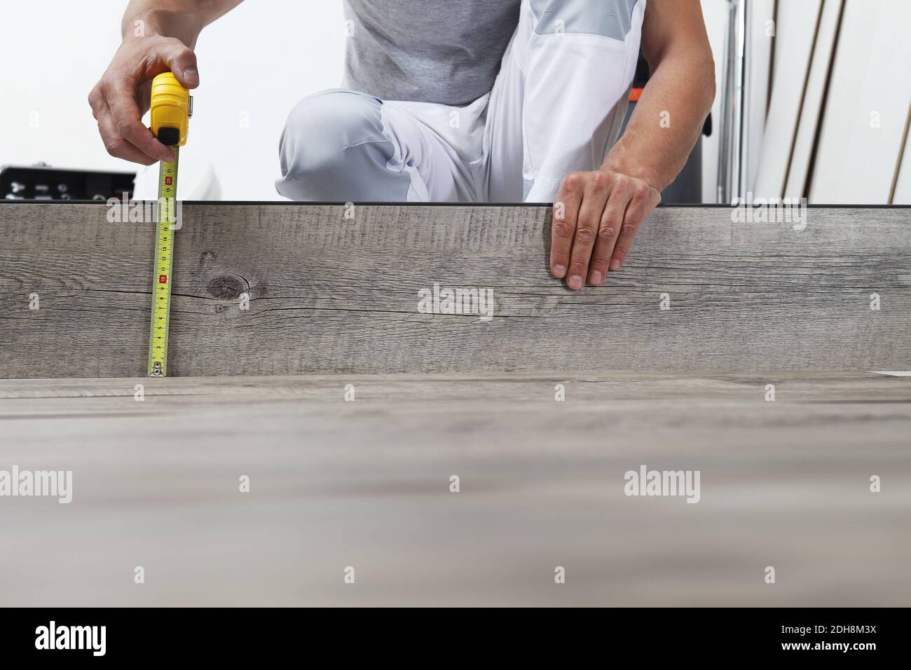 Worker hands installing timber laminate vinyl floor, takes measurement