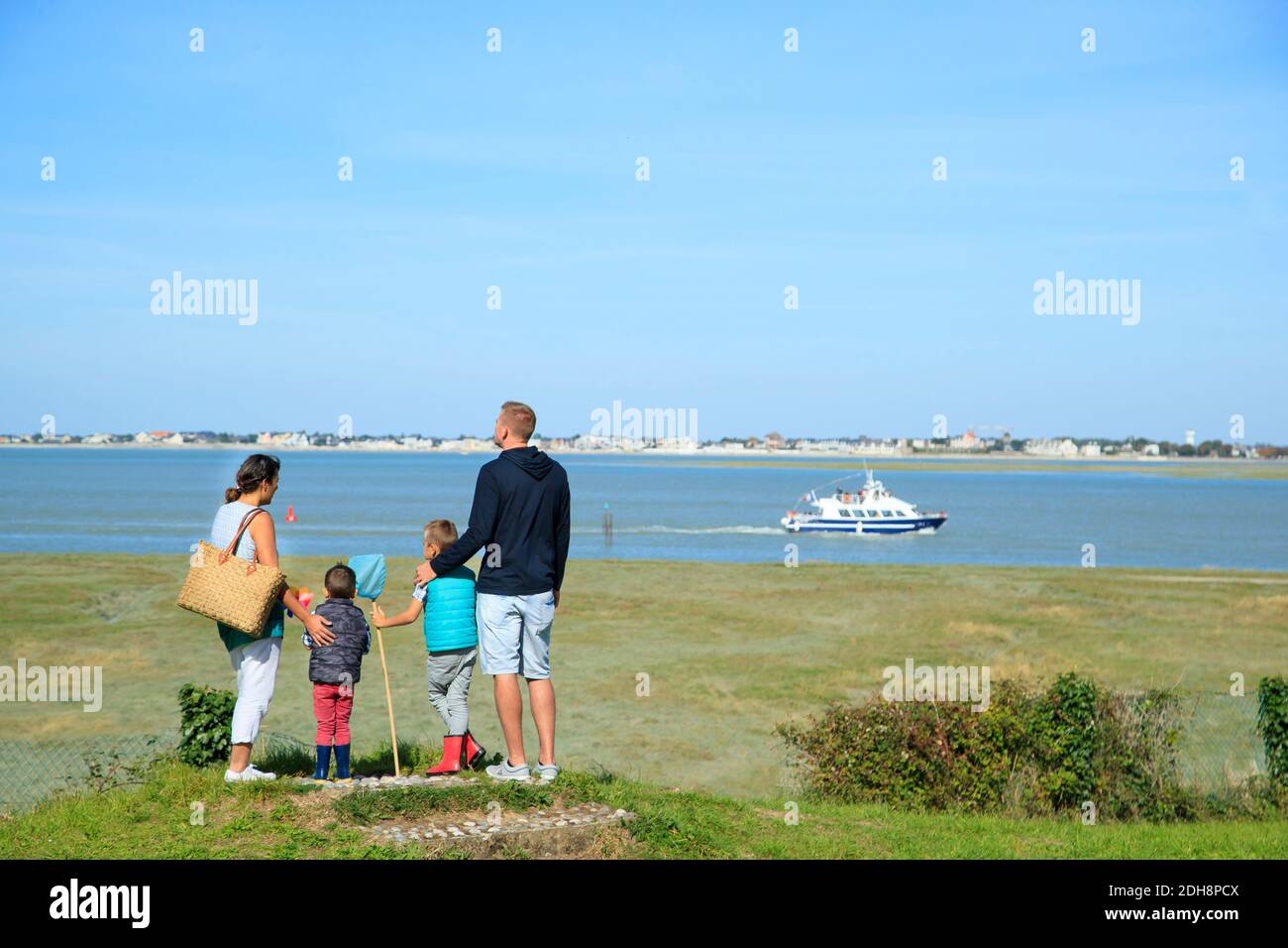 Somme Bay (northern France): family with two children facing the sea, looking at a sailboat on the water, in Saint-Valery-sur-Somme, along the coastal Stock Photo