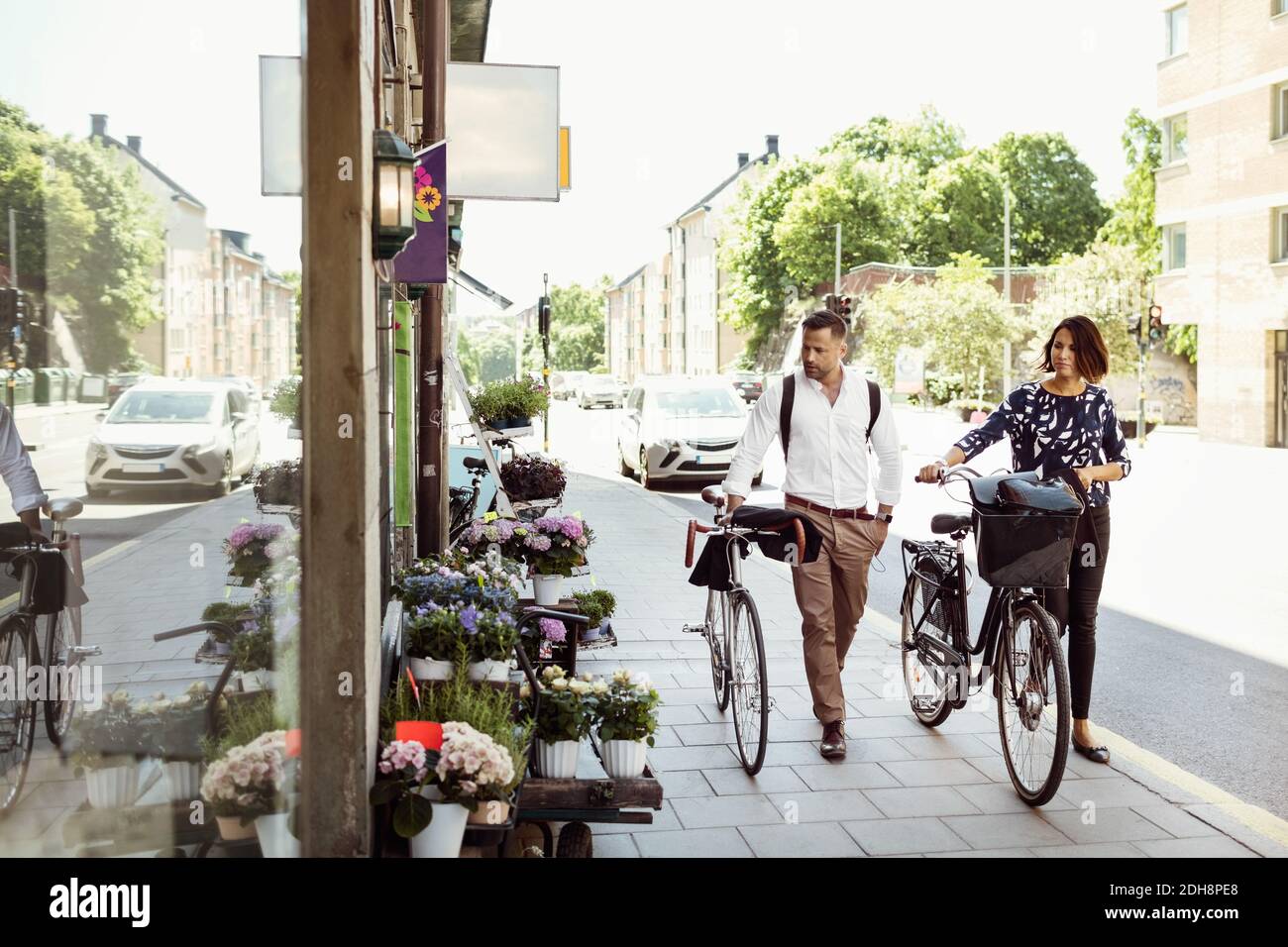 Business people with bicycles walking on sidewalk in city Stock Photo