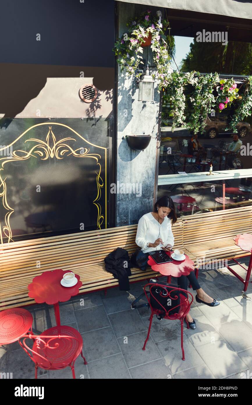 Businesswoman using smart phone at sidewalk cafe Stock Photo