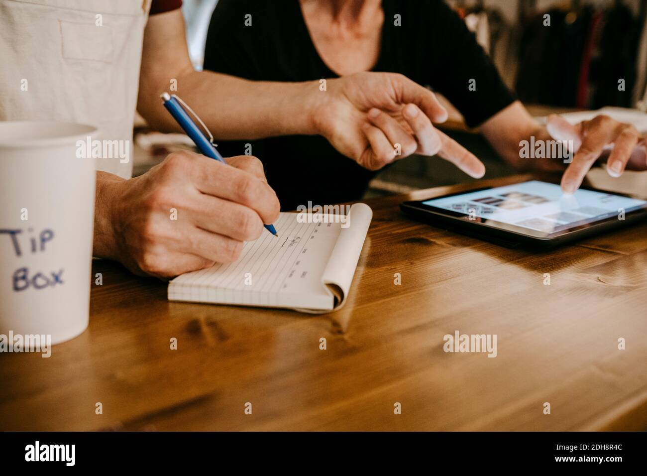Midsection of owners working while using digital tablet in coffee shop Stock Photo