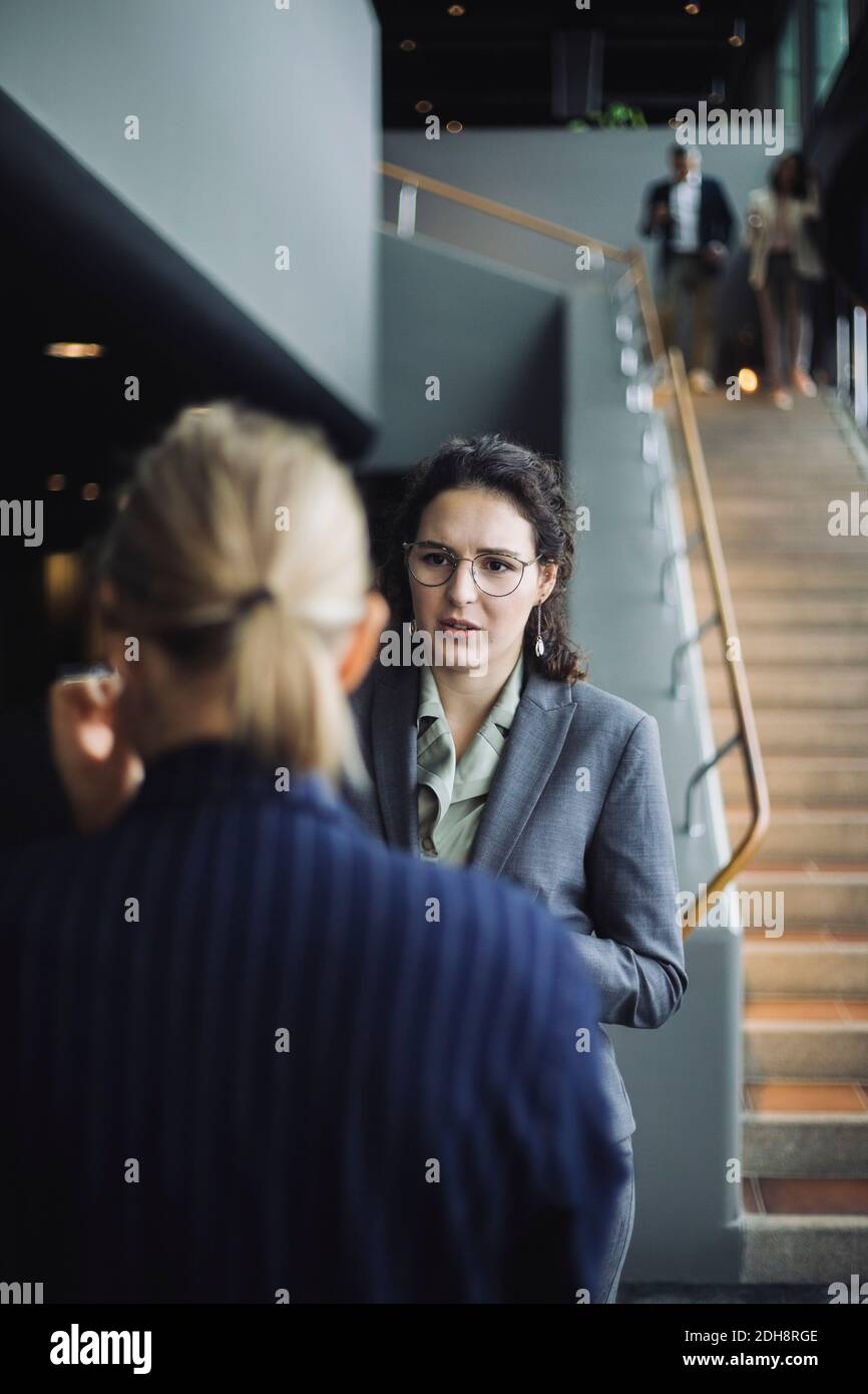 Female professional discussing with colleague at workplace Stock Photo