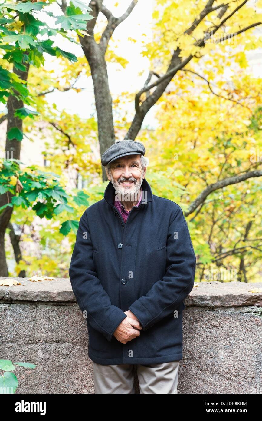 Portrait of happy senior man standing in park during autumn Stock Photo