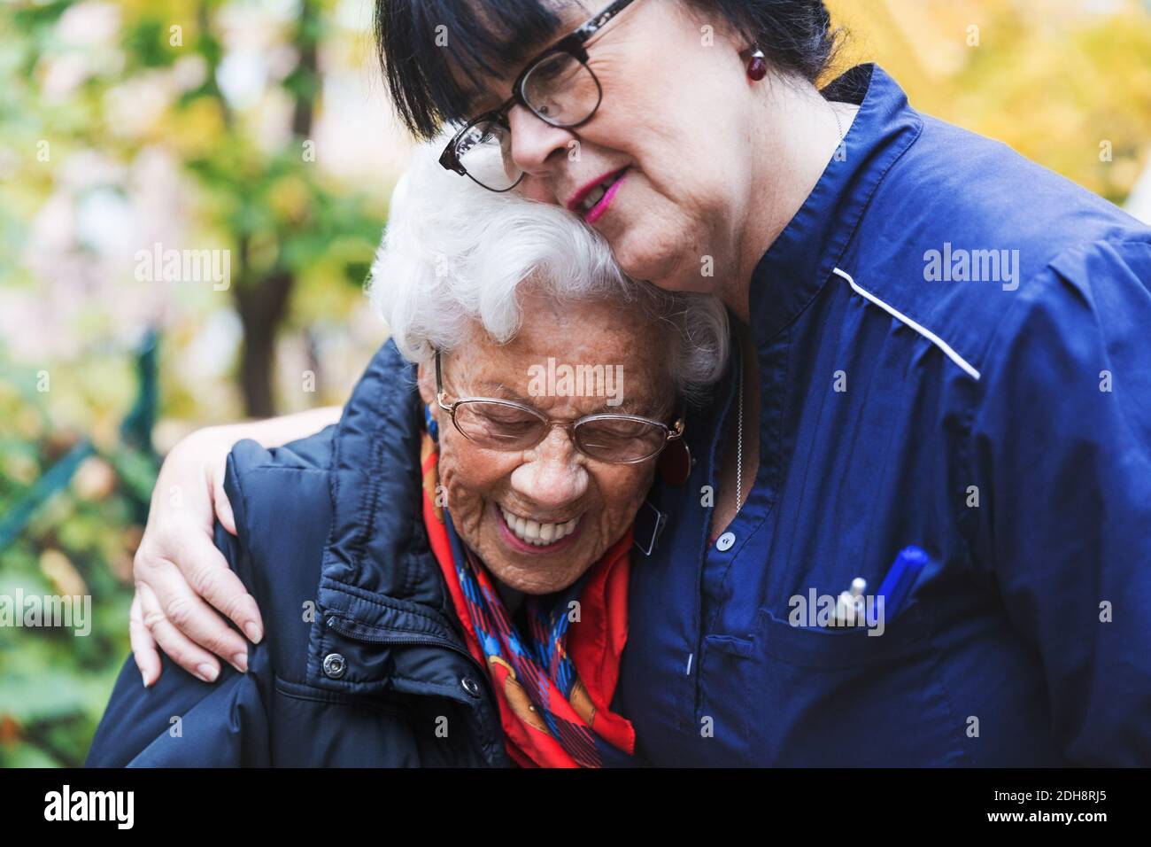 Caretaker embracing senior woman in park Stock Photo