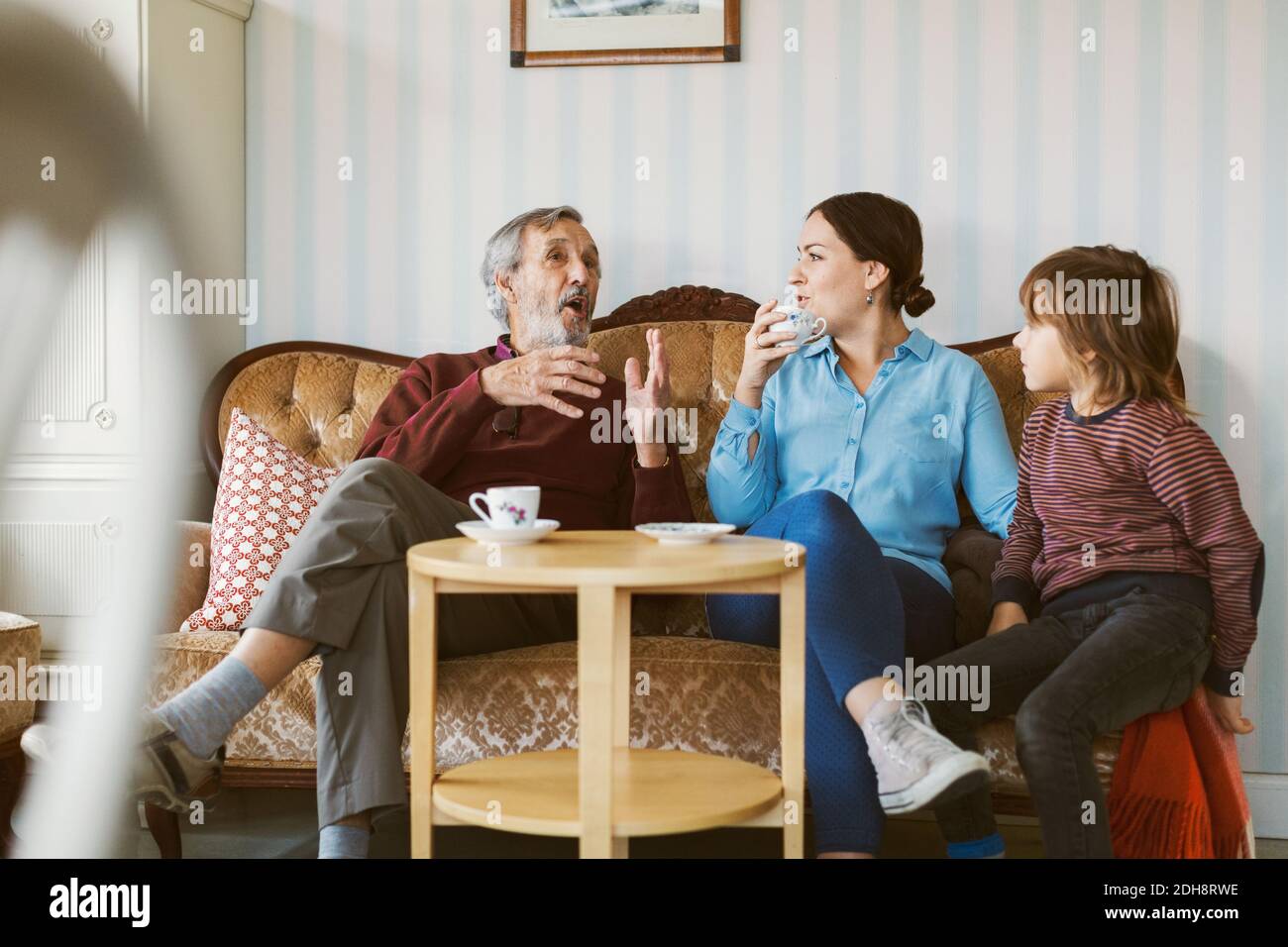 Senior man talking to daughter and great grandson on sofa in living room Stock Photo