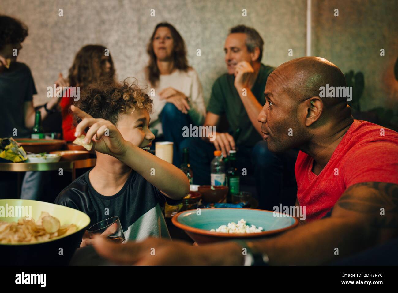 Smiling boy pointing while talking to mature man during sporting event Stock Photo