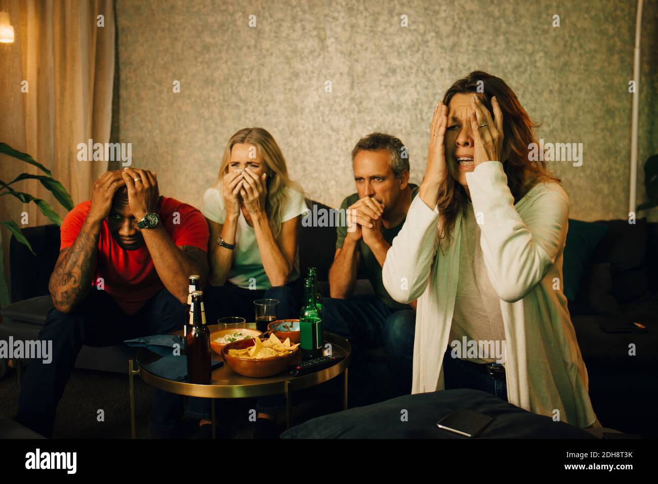 Disappointed heterosexual couples watching sports at night Stock Photo