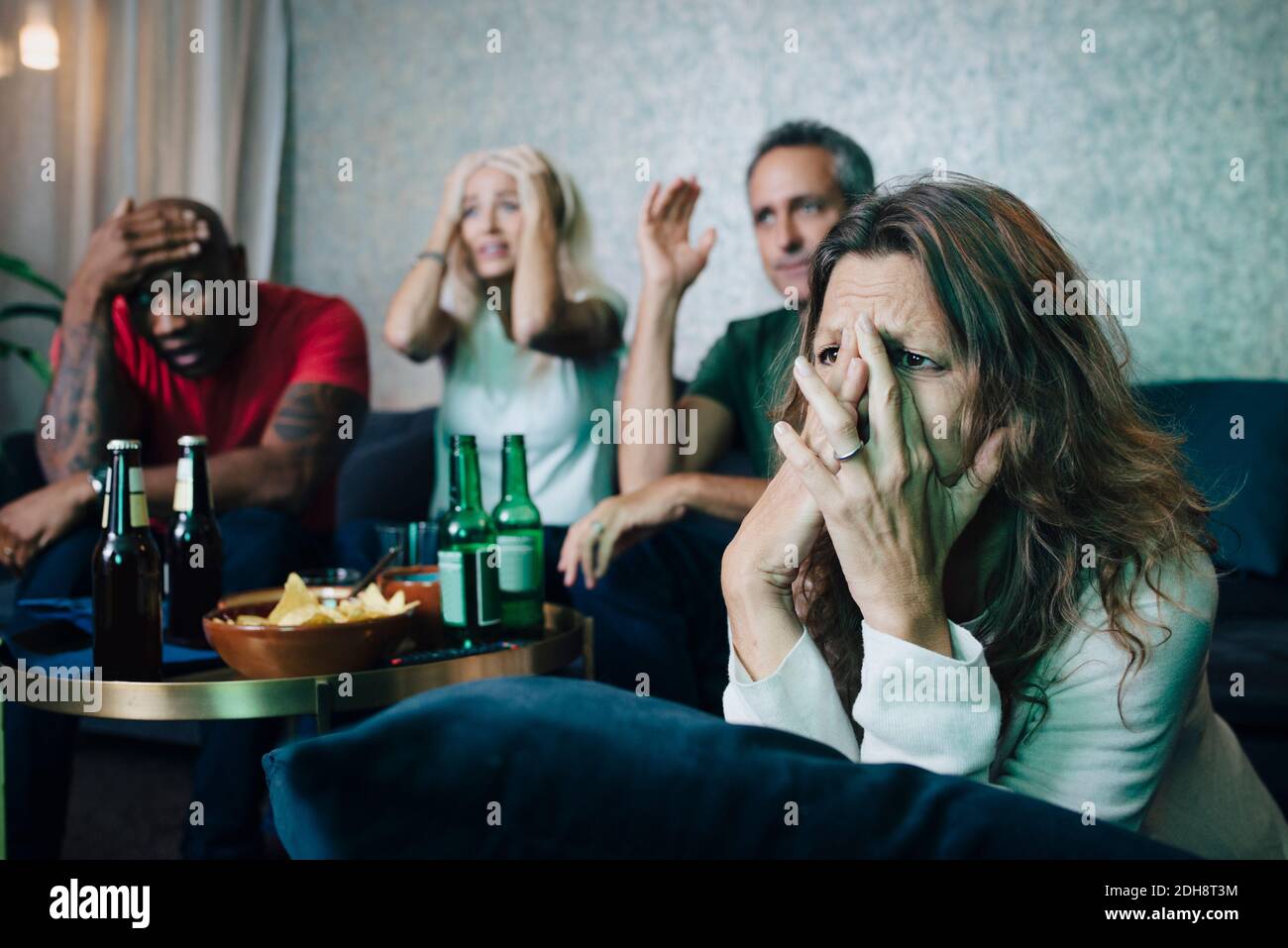 Disappointed couples watching sports in living room at night Stock Photo