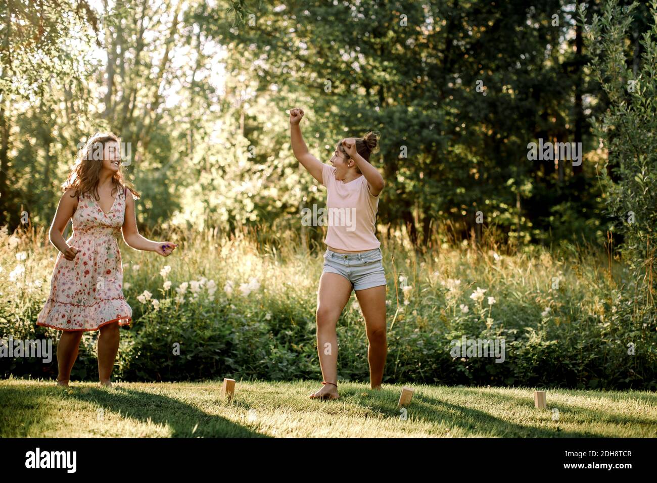 Happy siblings looking at each other while playing molkky in backyard Stock Photo