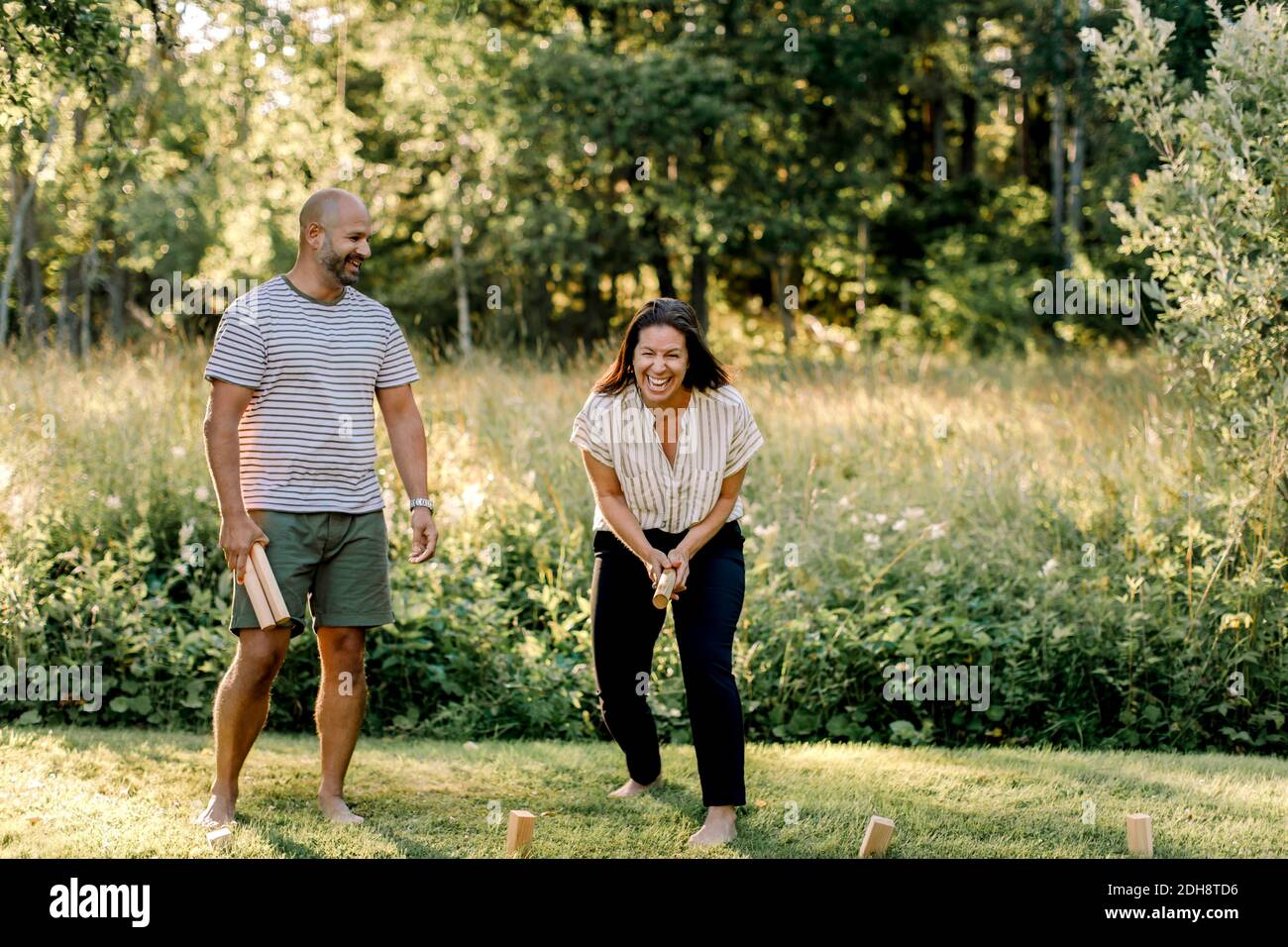 Cheerful woman with male partner playing molkky in yard Stock Photo