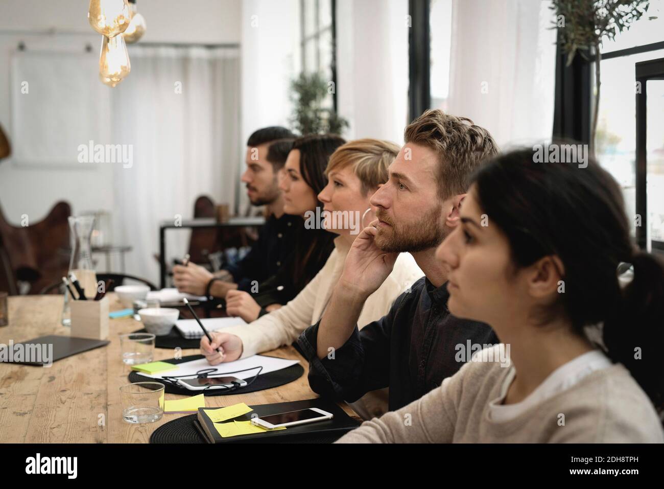 Side view of business people sitting at table in office Stock Photo