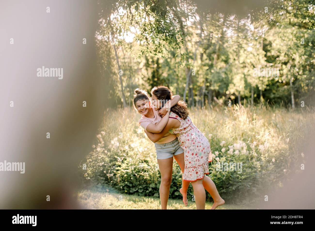 Portrait of happy girl embracing sibling in backyard Stock Photo