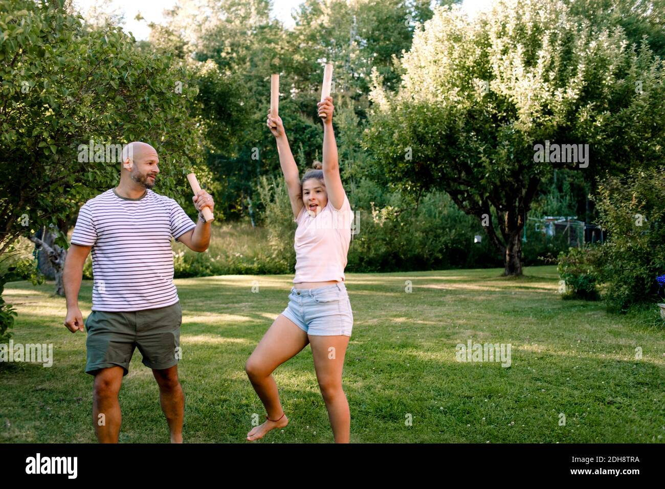 Father looking at daughter with hand raised while playing molkky in yard Stock Photo