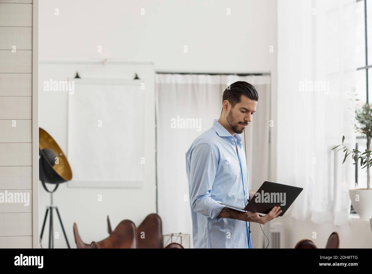 Businessman using laptop while standing at table in office Stock Photo